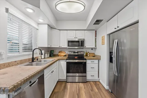 a kitchen with stainless steel appliances granite countertop a refrigerator a stove and a sink