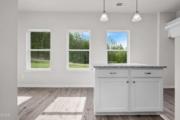 an empty room with wooden floor cabinet and windows