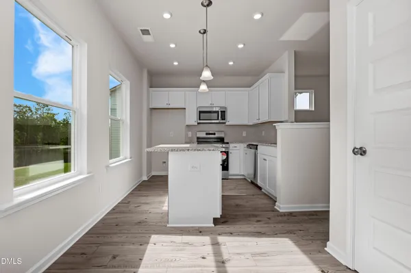 a kitchen with kitchen island a counter top space a sink stainless steel appliances and cabinets