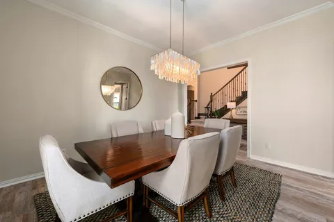 a dining room with wooden floor a chandelier a wooden table and chairs