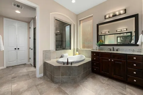 a spacious bathroom with a tub sink and a mirror