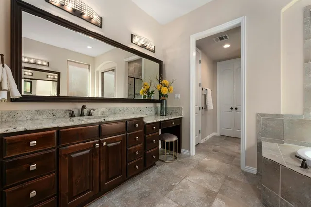 a spacious bathroom with a granite countertop sink and a mirror