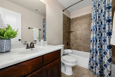 a bathroom with a sink a toilet a mirror a bathtub and shower