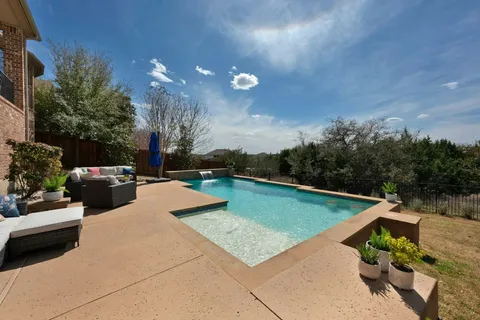 a view of a swimming pool with a patio and a yard