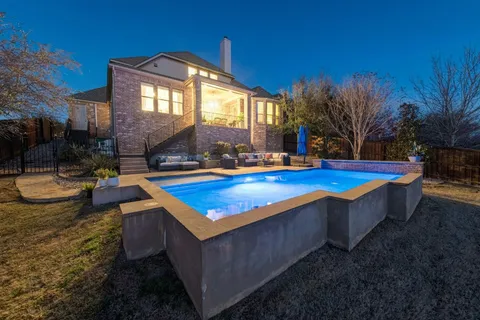 a view of swimming pool with outdoor seating and house in the background