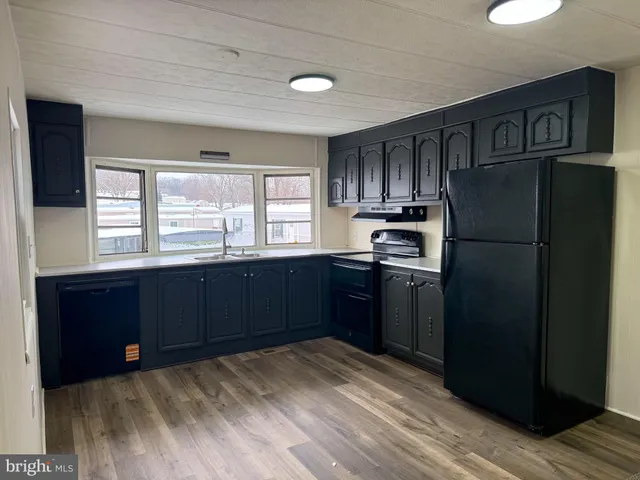 a kitchen with granite countertop stainless steel appliances a refrigerator cabinets and wooden floor