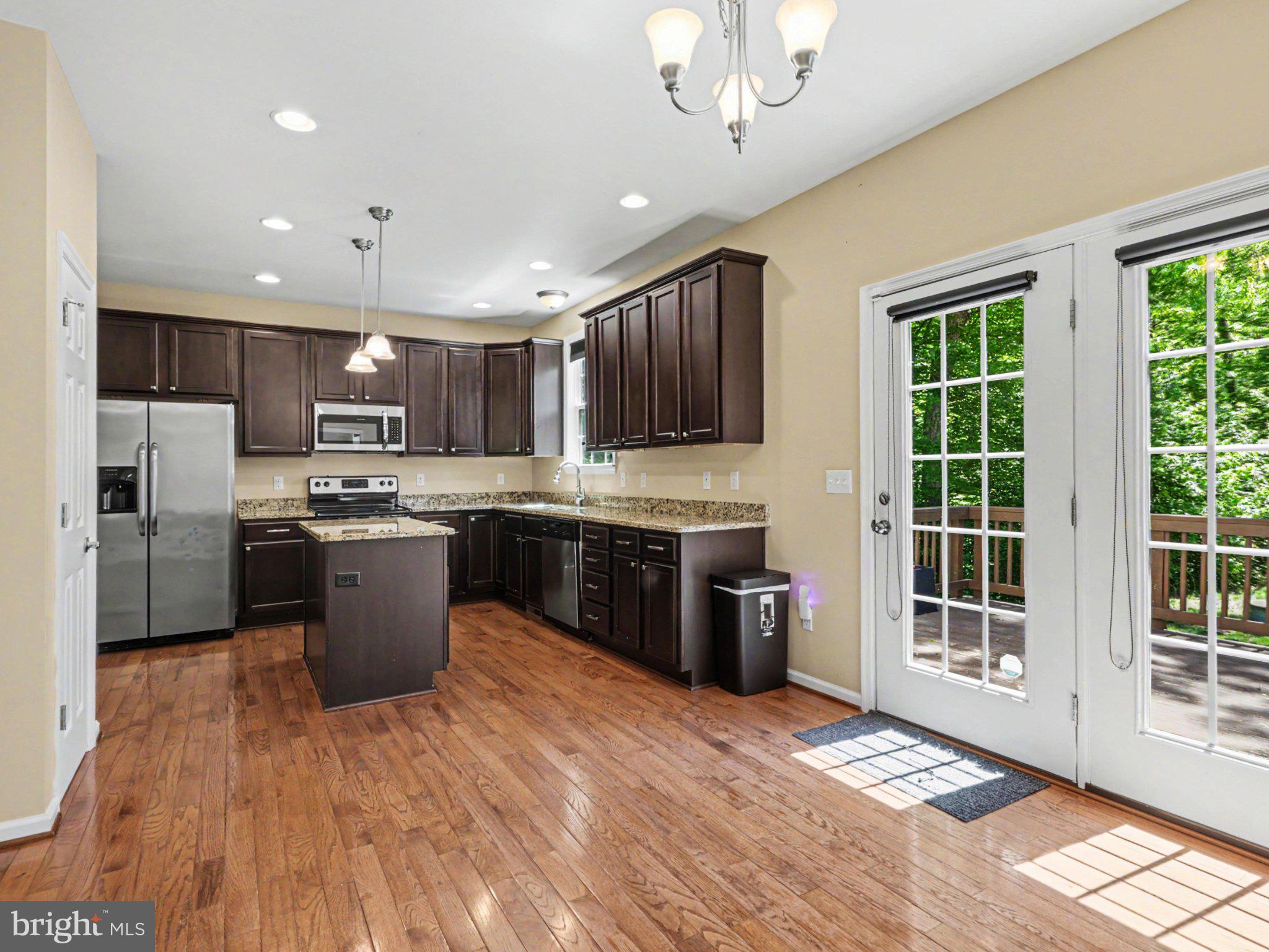 9811 Catharpin Road Spotsylvania, VA 22551 - Photo 7 of 30 a large kitchen with stainless steel appliances granite countertop a stove a sink dishwasher a microwave oven and a refrigerator with wooden floor