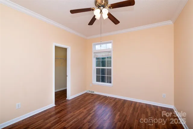 an empty room with wooden floor closet and windows