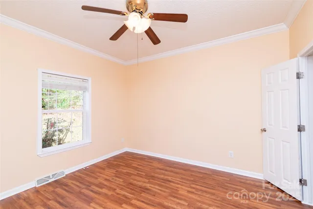 an empty room with wooden floor fan and windows