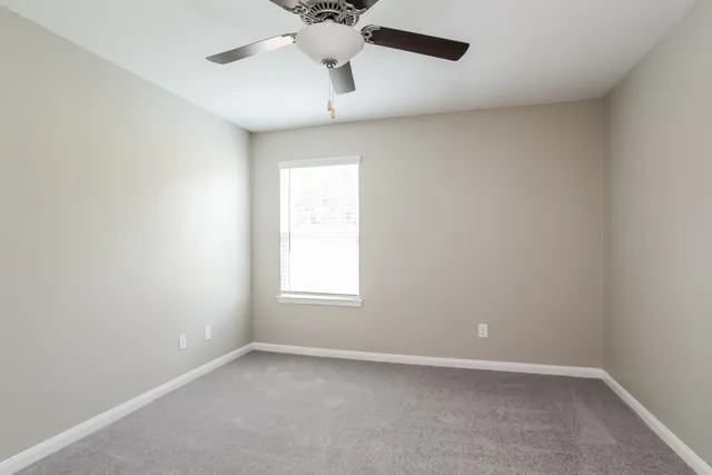 an empty room with a window and a fan