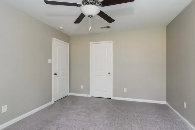 a view of an empty room and chandelier fan