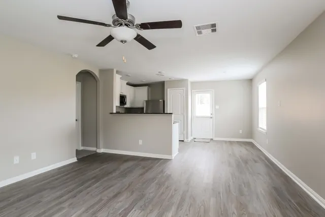 a view of empty room with wooden floor and ceiling fan