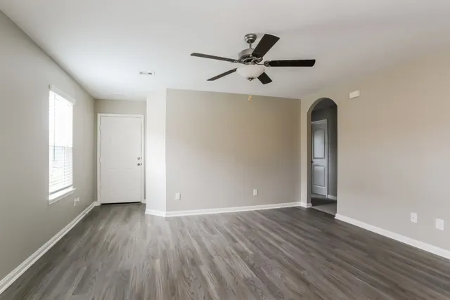 an empty room with wooden floor closet and windows