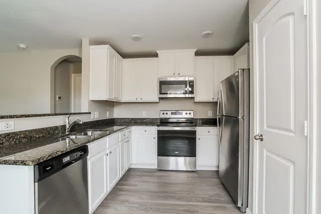 a kitchen with stainless steel appliances granite countertop a refrigerator and a stove top oven