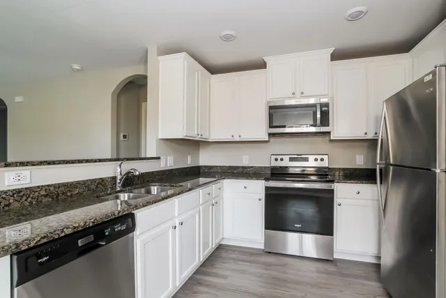 a kitchen with stainless steel appliances granite countertop a stove a sink and a refrigerator