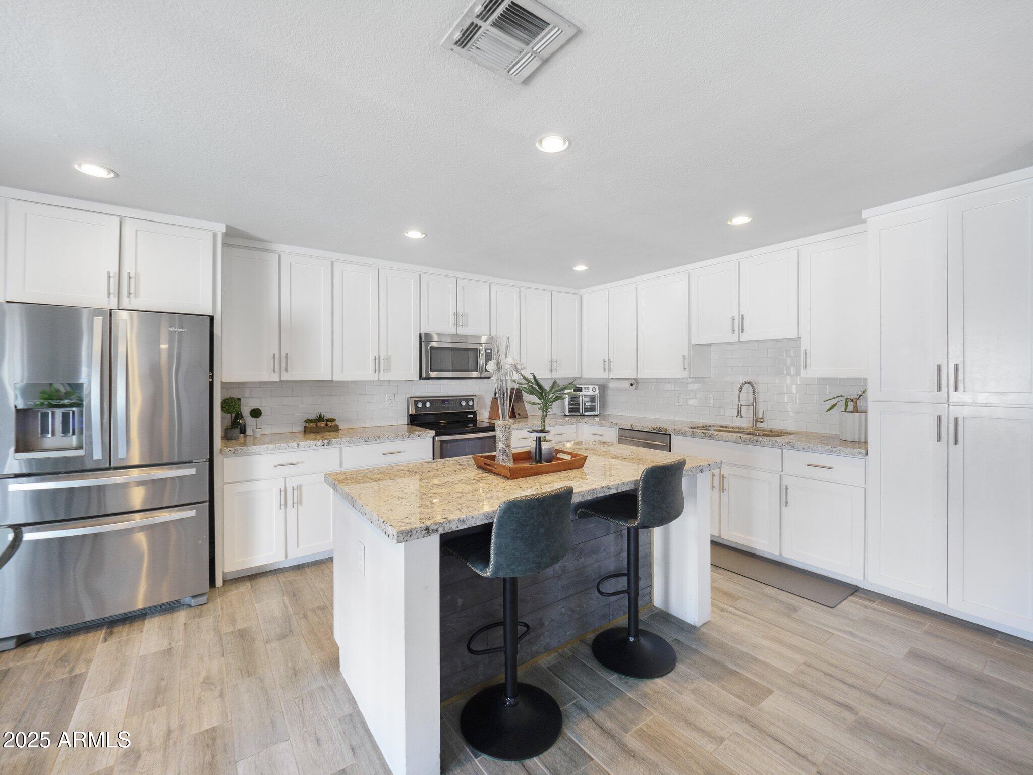 8728 East Monte Vista Road Scottsdale, AZ 85257 - Photo 7 of 28 a kitchen with a sink a refrigerator and white cabinets