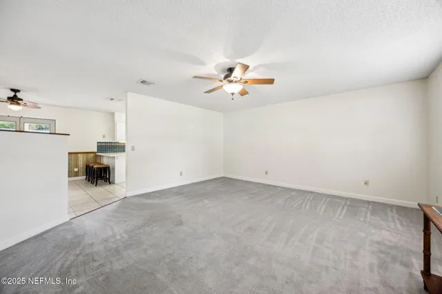 an empty room with windows and chandelier fan