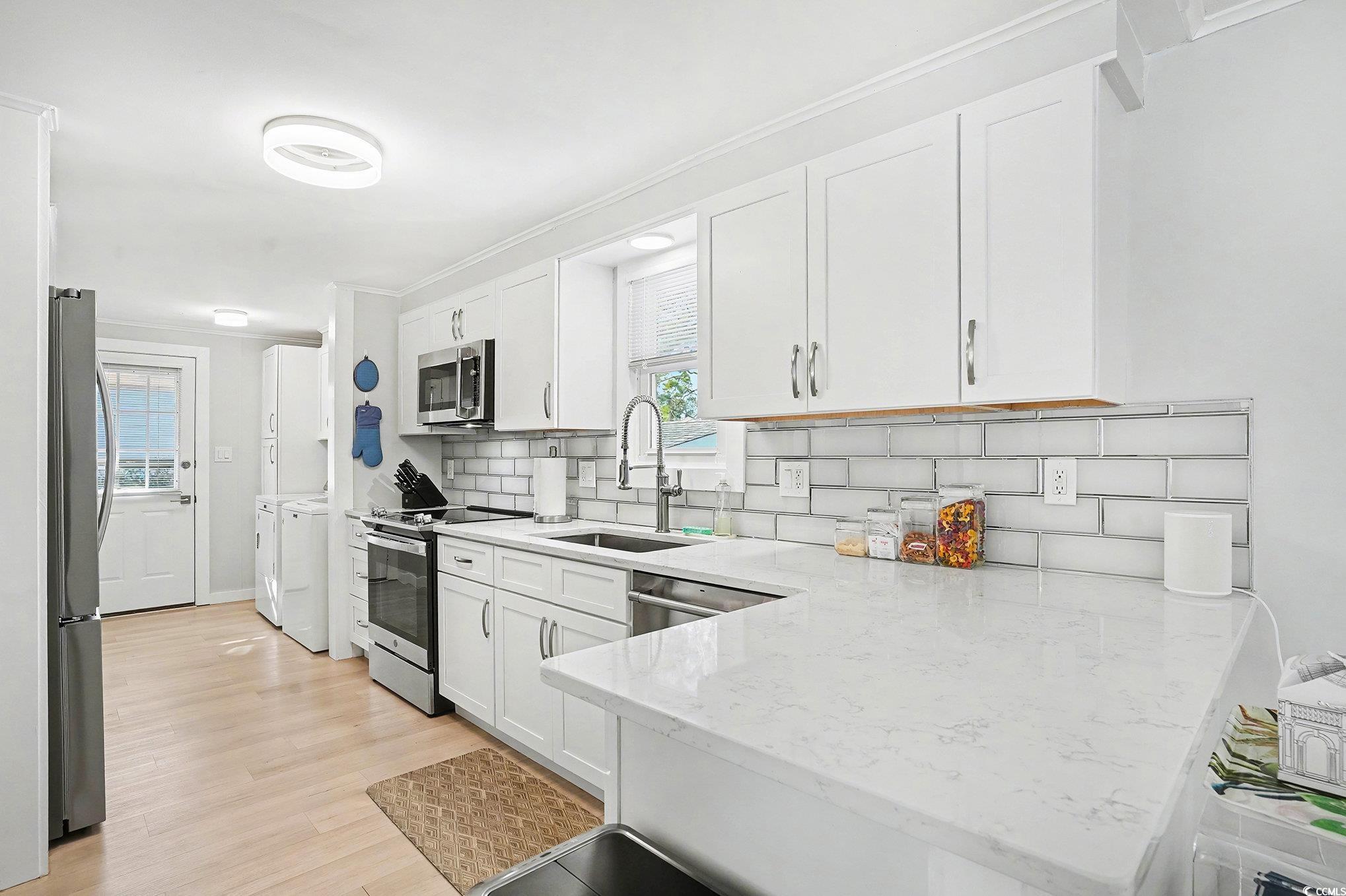 3268 Pecan Trail Murrells Inlet, SC 29576 - Photo 11 of 38 Kitchen featuring white cabinets, a peninsula, light stone countertops, stainless steel appliances, and tasteful backsplash