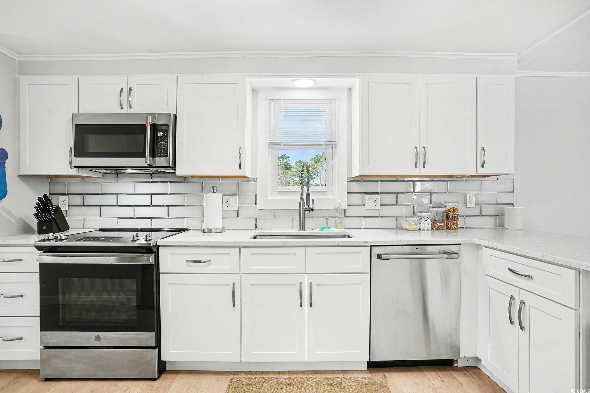 3268 Pecan Trail Murrells Inlet, SC 29576 - Photo 12 of 38 Kitchen with white cabinetry, appliances with stainless steel finishes, light stone countertops, light wood-style floors, and ornamental molding