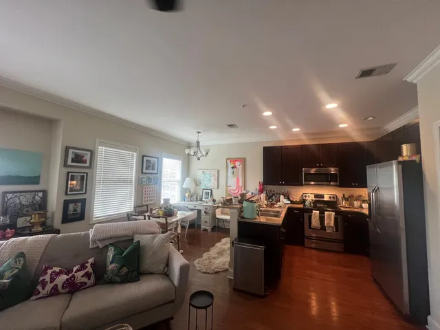 a living room with stainless steel appliances kitchen island granite countertop a refrigerator a stove a oven a dining table and chairs