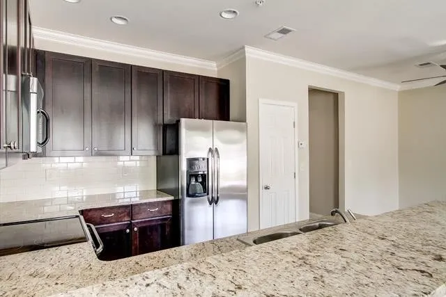 a kitchen with granite countertop wooden cabinets and refrigerator