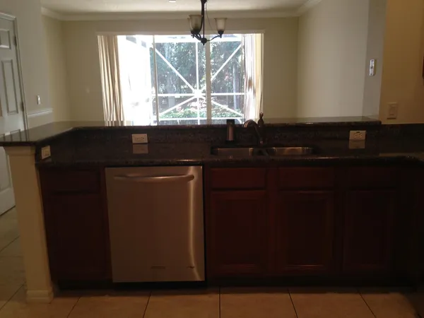 a kitchen with granite countertop a sink window and cabinets