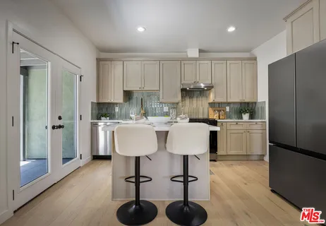 a kitchen with a sink a refrigerator and white cabinets