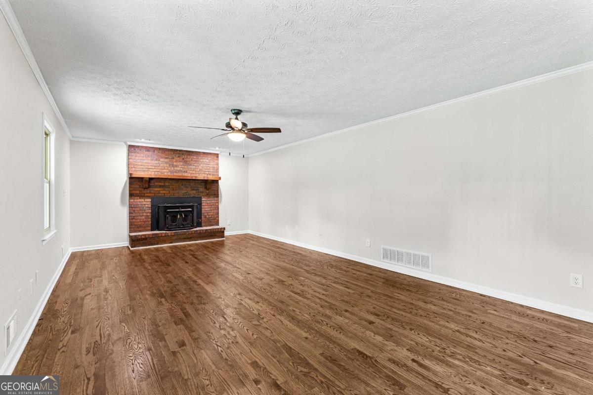 550 Davis Road Fayetteville, GA 30215 - Photo 11 of 75 a view of empty room with wooden floor and fireplace