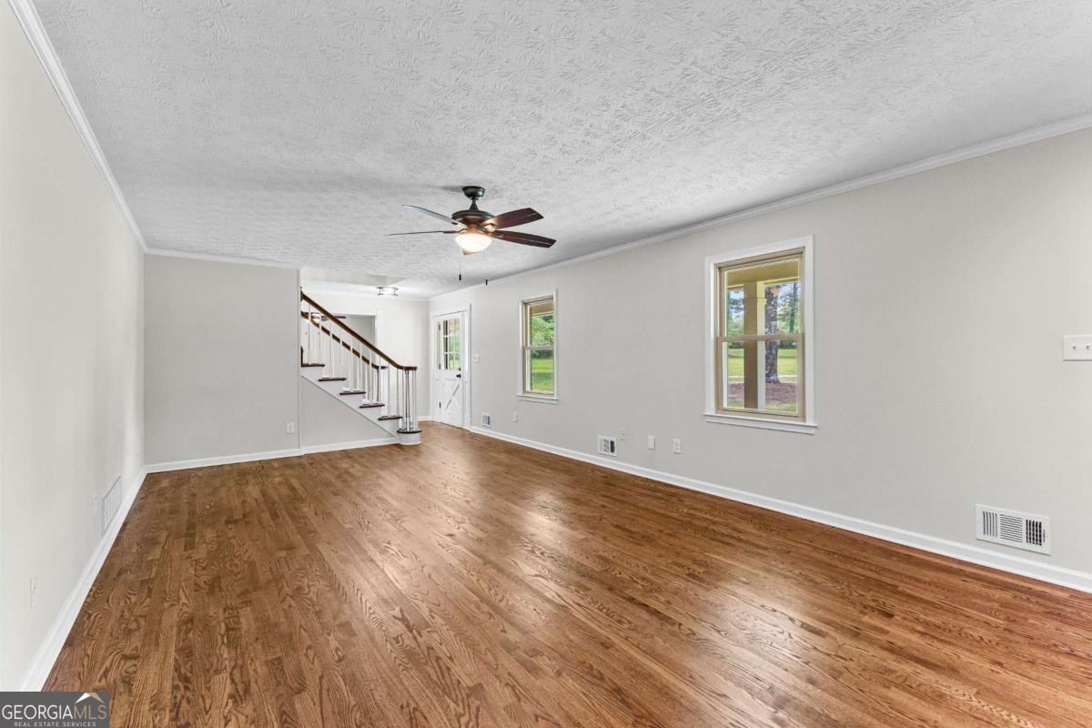 550 Davis Road Fayetteville, GA 30215 - Photo 15 of 75 a view of empty room with wooden floor and fan