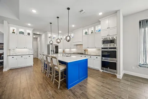 a kitchen with stainless steel appliances kitchen island granite countertop a wooden floors and a view of living room