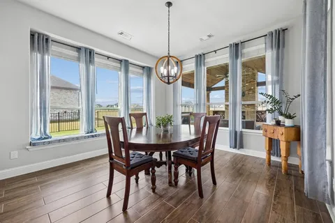 a dining room with furniture a chandelier and wooden floor