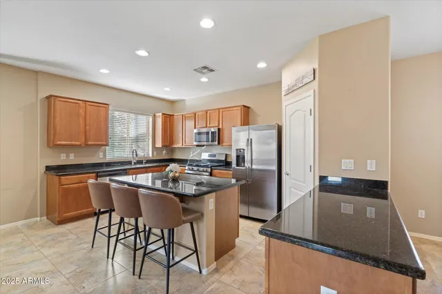 a kitchen with stainless steel appliances granite countertop a stove a refrigerator a sink a stove with white cabinets and wooden floor