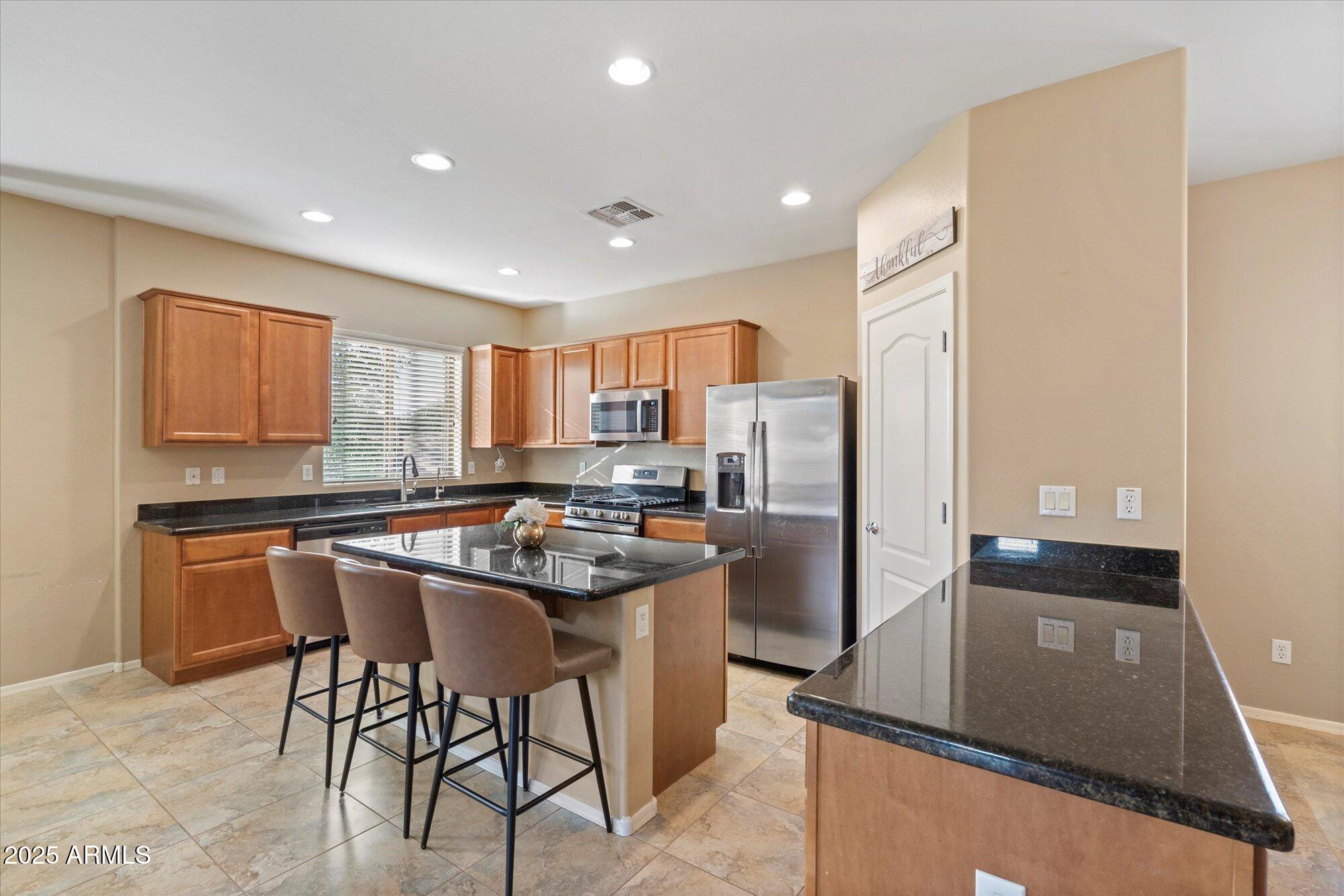 6710 South Seton Avenue Gilbert, AZ 85298 - Photo 11 of 51 a kitchen with stainless steel appliances granite countertop a stove a refrigerator a sink a stove with white cabinets and wooden floor