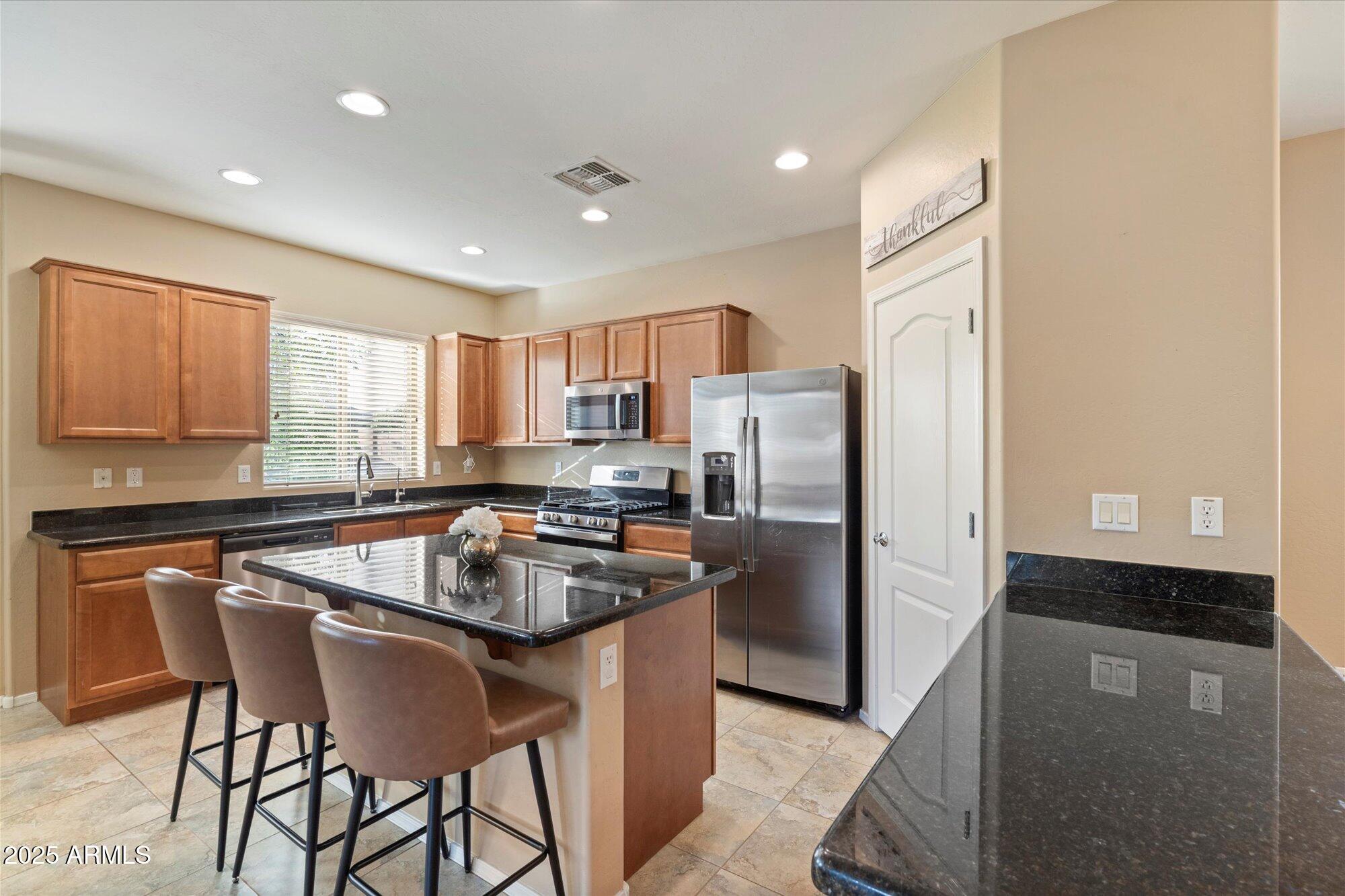 6710 South Seton Avenue Gilbert, AZ 85298 - Photo 12 of 51 a kitchen with stainless steel appliances granite countertop a refrigerator a stove a sink a dining table and chairs