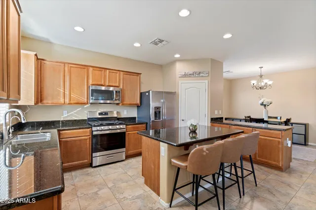 a kitchen with stainless steel appliances granite countertop a stove top oven a sink dishwasher a dining table and chairs