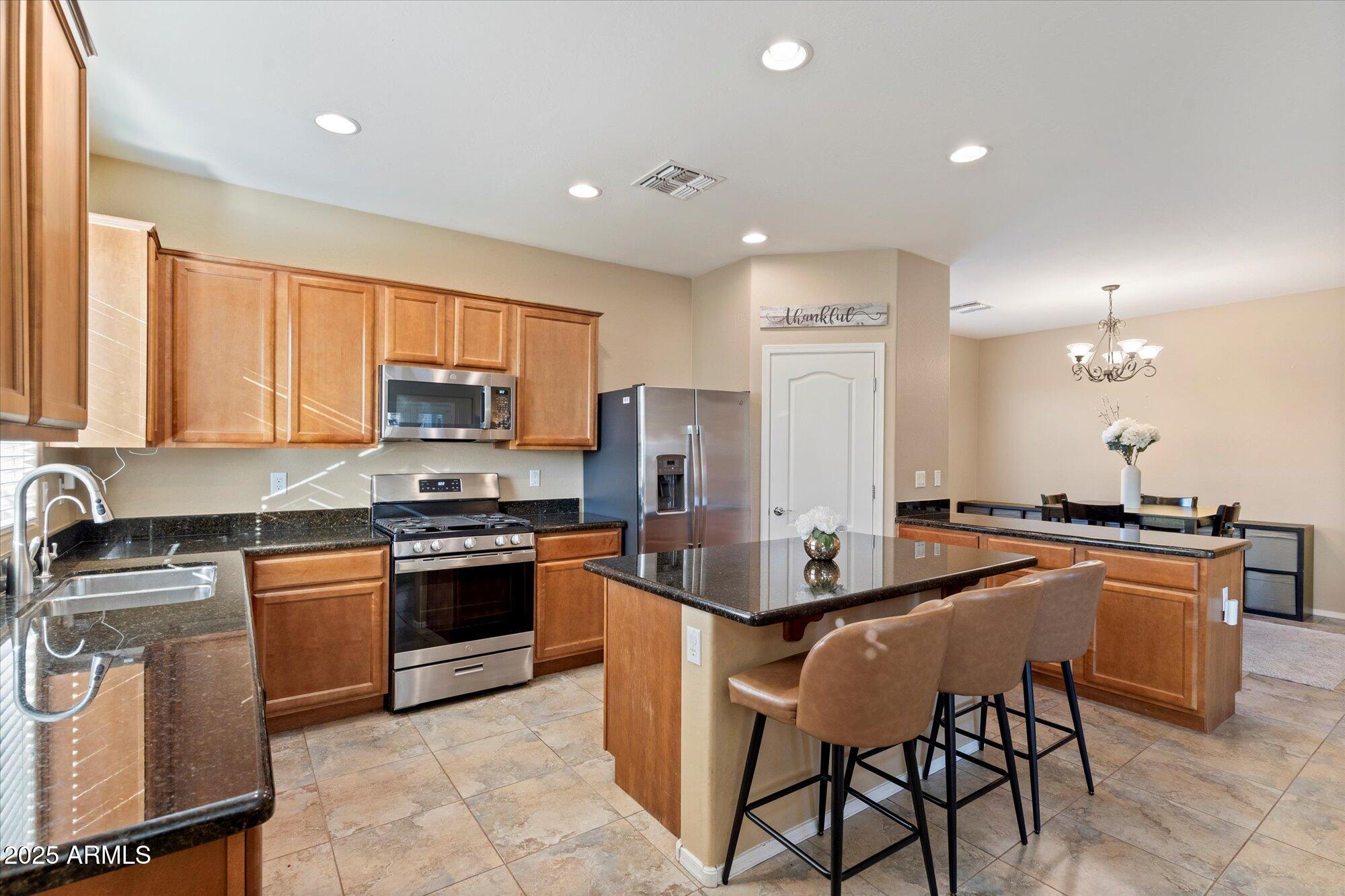 6710 South Seton Avenue Gilbert, AZ 85298 - Photo 13 of 51 a kitchen with stainless steel appliances granite countertop a stove top oven a sink dishwasher a dining table and chairs