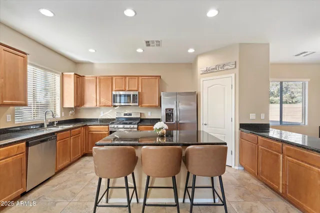 a kitchen with stainless steel appliances granite countertop a sink a stove a refrigerator cabinets and chairs