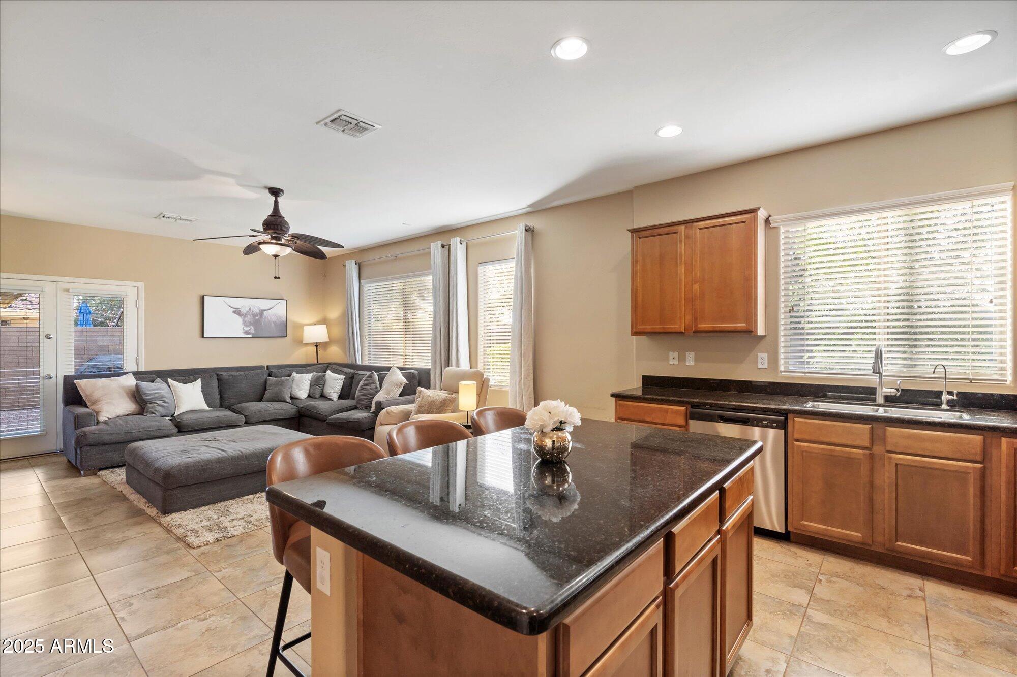 6710 South Seton Avenue Gilbert, AZ 85298 - Photo 17 of 51 a kitchen with a stove a sink a kitchen island with a dining table and chairs