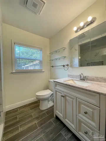 a bathroom with a granite countertop toilet sink and mirror