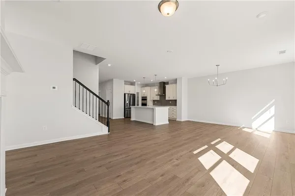 a view of kitchen and empty room with wooden floor