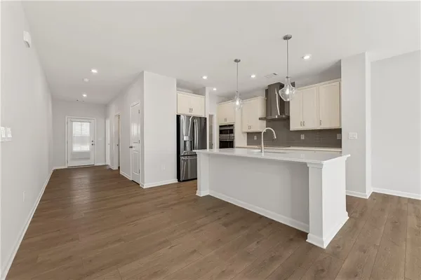 a large white kitchen with kitchen island a sink wooden floor white stainless steel appliances and cabinets