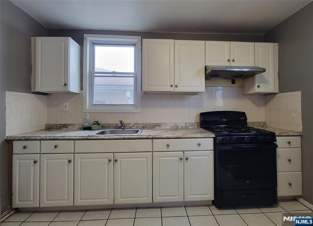 6 6th Street Harrison, NJ 07029 - Photo 5 of 12 a kitchen with white cabinets and a stove top oven
