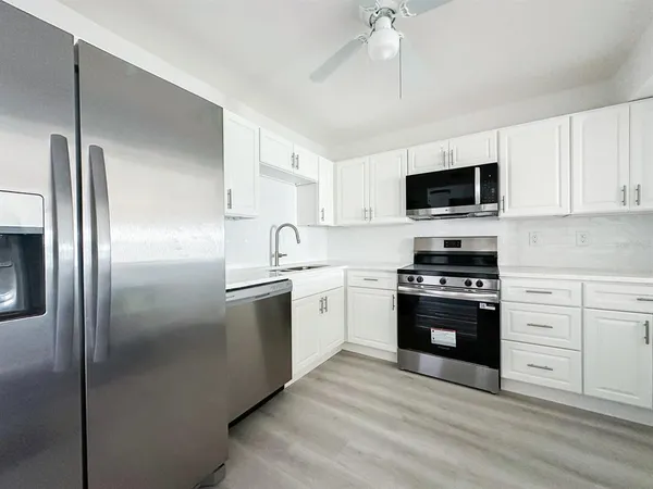 a kitchen with stainless steel appliances kitchen island granite countertop a refrigerator stove and sink