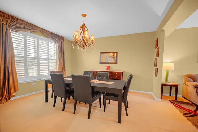 a view of a dining room with furniture a chandelier and a window