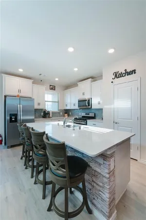 a kitchen with stainless steel appliances a table chairs refrigerator and cabinets