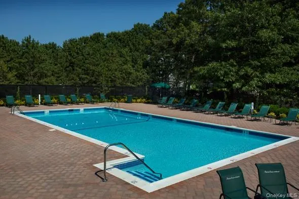 a view of a swimming pool with lawn chairs under an umbrella