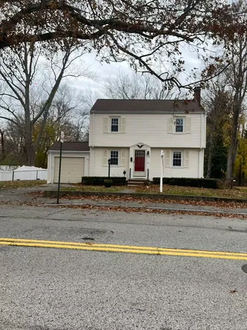 a view of a house with a yard and a large tree