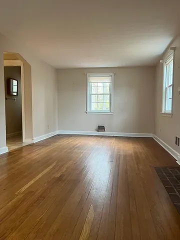 a view of an empty room with wooden floor and stairs