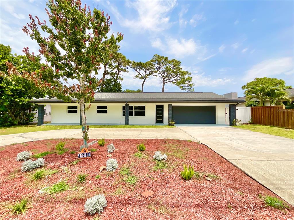 1290 Michigan Boulevard Dunedin, FL 34698 - Photo 1 of 45 a front view of a house with a yard and garage