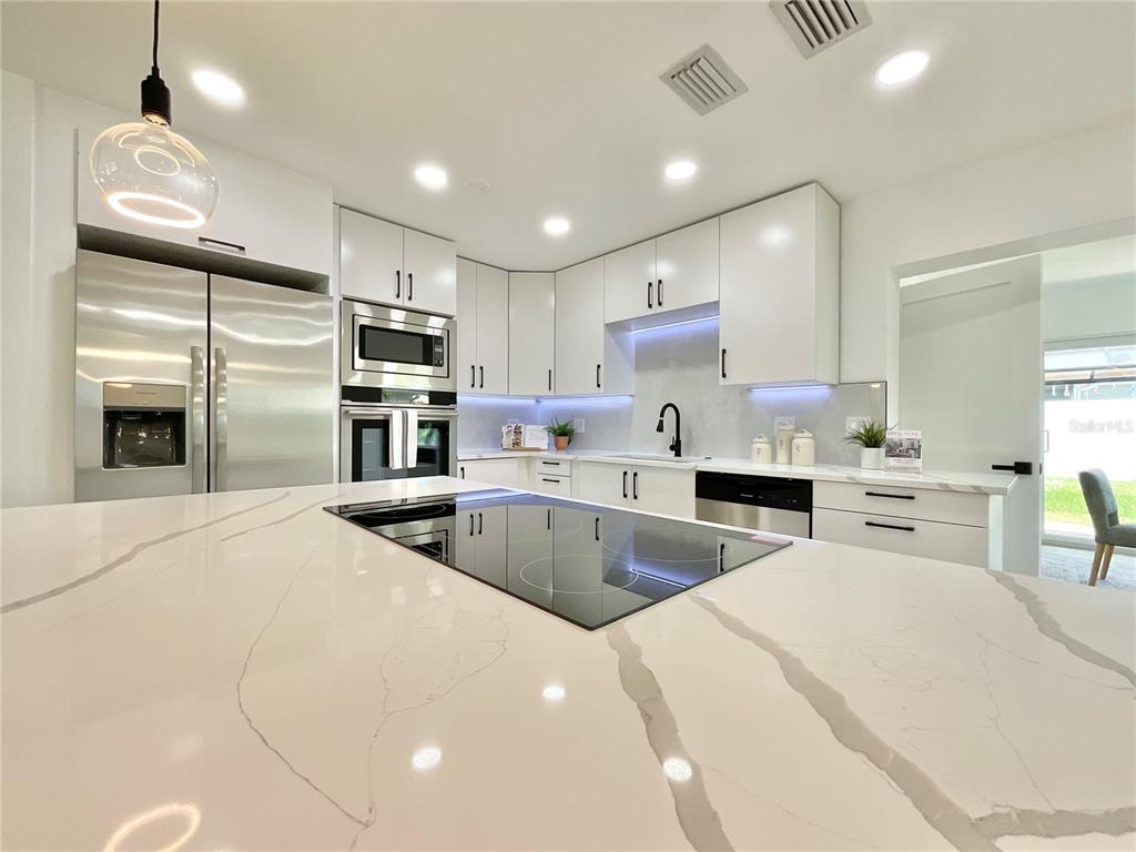 1290 Michigan Boulevard Dunedin, FL 34698 - Photo 8 of 45 a kitchen with stainless steel appliances kitchen island granite countertop a stove refrigerator and cabinets
